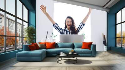 Young attractive female sitting at table with raised arms Wall mural