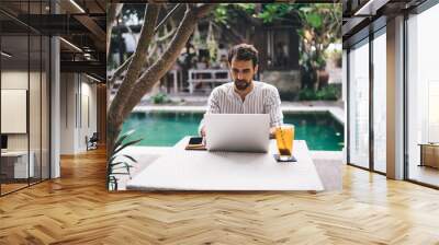 Young bearded man working on laptop Wall mural