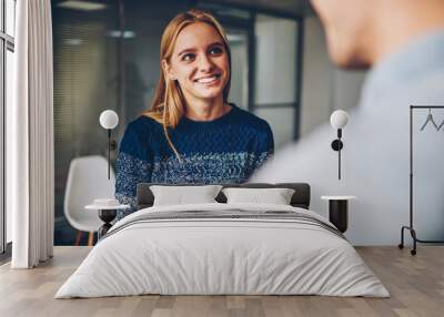 Young blonde woman smiling while answering questions during interview for getting job offer in office,happy female communicating with colleague during work break enjoying friendly atmosphere Wall mural