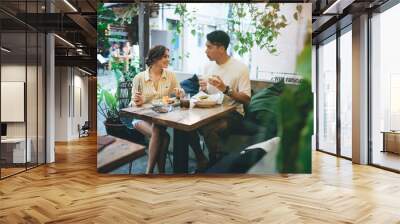 Young couple having lunch and chatting in cafe Wall mural