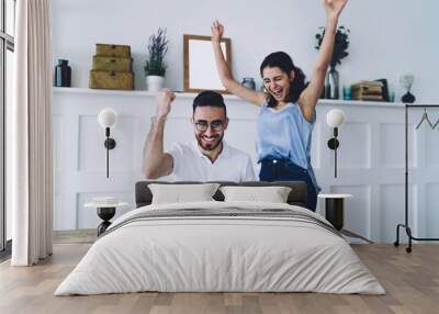 Young happy couple smiling with look of success and looking at laptop Wall mural