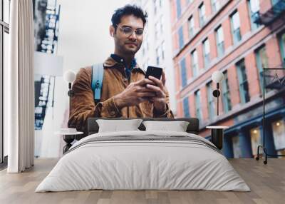 Young Hispanic man typing on smartphone on New York street Wall mural