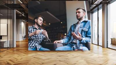 Young modern men talking together while drinking in cafe Wall mural