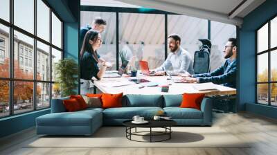 Young team of professionals discussing ideas and effective solutions for improving work process at meeting table during brainstorming in modern office.Employees collaborating on business project Wall mural