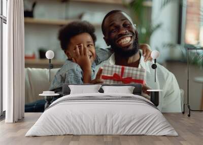 Congratulating his black father with a wrapped gift indoors Wall mural