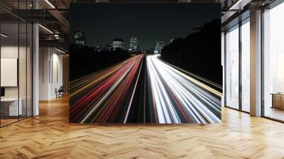 It's a long exposure photograph of light trails on a highway, a motorway and a junction in a big city. At night, high speed motion blur and light trails appear on a highway motorway. Wall mural