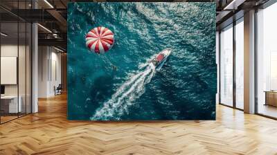 Taking off on a parachute behind a boat while on vacation by the sea in a resort. Beautiful blue water and red and white parachute. Wall mural