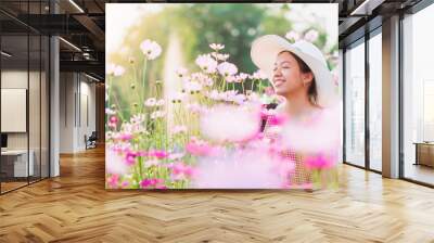 Asian beautiful young woman walking and take photo in Cosmos flower field landscape background.Concept of travel in summer season at Thailand. Wall mural