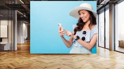 Asian pretty woman tourist preparing for travel and using smartphone isolated on blue banner background.Concept of people using technology of travel. Wall mural