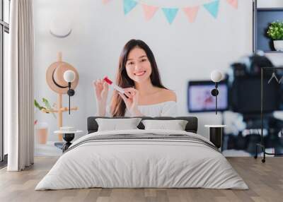 Beautiful asian woman blogger is showing how to make up and use cosmetics. In front of the camera to recording vlog video live streaming at home.Business online influencer on social media concept. Wall mural