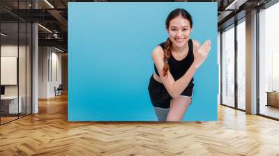 Portrait of confident beautiful asian fitness woman warm up before exercise isolated on blue color background with copy space.Concept of slim and healthy happy girl workout. Wall mural