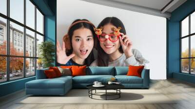 Young beautiful Asian woman Photo poses with costumes during the Christmas season with best friend.Smiling face in room with white wall background for holiday festival.Christmas Party celebration Wall mural