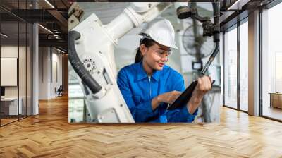 Close up engineer woman looking at tablet and read instruction on how to use robotic arm machine in the factory. Worker wearing safety helmet, glasses and uniform. Technology and industrial from ai Wall mural