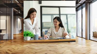 Two happy young women discussing business while working together at the creative office Wall mural