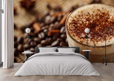 A close-up of a cappuccino with cinnamon sprinkled on top, surrounded by coffee beans and warm tones Wall mural