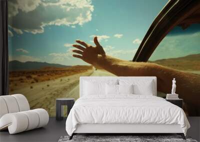 Hand hanging out of the car window, feeling the breeze, with a scenic road ahead Wall mural