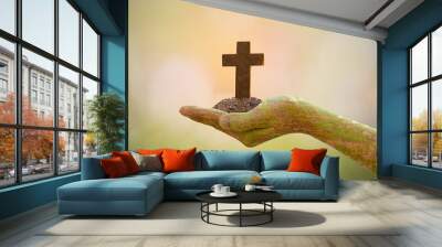 Human hand holding cross on blurred nature background. Wall mural