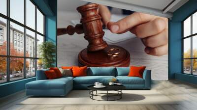 Husband signing divorce contract. Man's hand, gavel of judge and rings close-up. Divorce concept. Wall mural