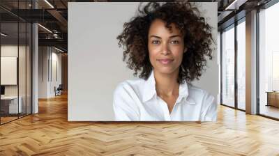 Happy woman with curly hair, standing with arms folded, simple white backdrop, casual white shirt, isolated, natural beauty and confidence, copy space Wall mural