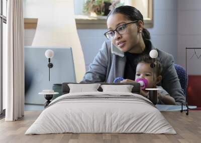 Mother holding baby and working at her computer Wall mural