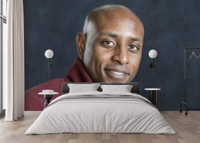 Portrait of a black man with a shaved head smiing at the camera Wall mural