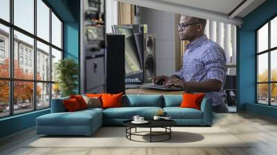 young professional man standing at his computer in the office Wall mural