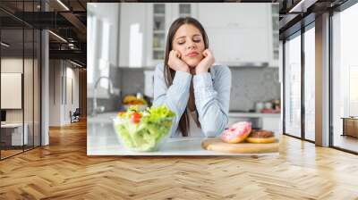 Teenage girl chooses between donuts and vegetable salad. Dilemma concept. Wall mural