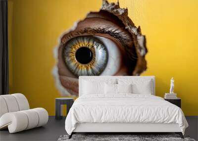 Curiosity through the keyhole: conceptual close-up of an eye on yellow wall Wall mural