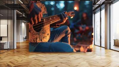 A musician strums a guitar by a campfire, the focus tight on their fingers and the strings. The rest of the group, engaged and singing along, is blurred into a backdrop of stars an Wall mural