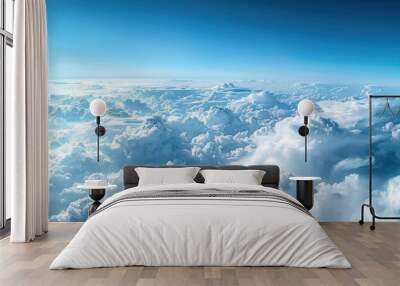 A stunning aerial panorama of dense cumulus clouds bathed in sunlight, with a clear blue sky above. Wall mural