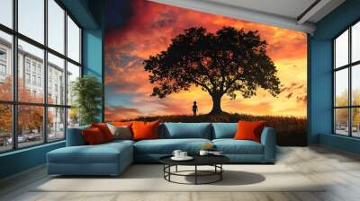 Silhouetted Child and Tree Against Dramatic Sunset Sky Wall mural