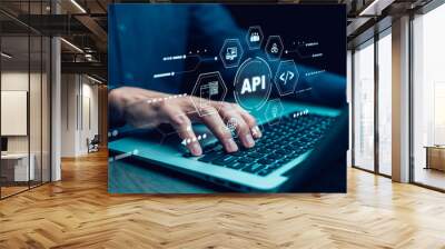 Businessman using laptop with API  icon on a virtual screen in the background of technology device internet, API Application Programming Interface connects services on the internet data communication. Wall mural