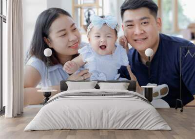 portrait of a young Asian family with a baby relaxing in the living room, happy family, and healthcare Wall mural