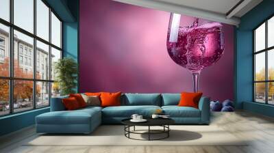 A glass of pink liquid is poured into a wine glass. The liquid is a mix of wine and blueberry juice Wall mural