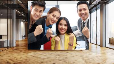 Group of young cheerful Asian business team working together in the office. Office business people with positive energy looking at camera with smiley face. Start up business strong teamwork. Wall mural