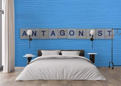 gray word antagonist from small wooden letters on a blue table Wall mural