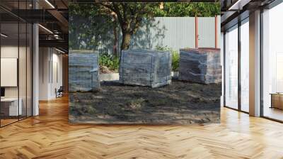 three square boxes in plastic packaging with paving bricks stand on gray ground outside Wall mural