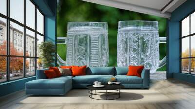 two large white empty crystal mug stand on a gray wooden table in the street on a green background Wall mural