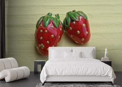 two small red plastic strawberry toys lie on a yellow table Wall mural