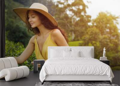 Traveler woman picking up green tea leaves in hand during her travel to famous nature landmark tea plantations in Nuwara Eliya, Sri Lanka. Gorgeous brunette Caucasian girl in stylish yellow dress and Wall mural