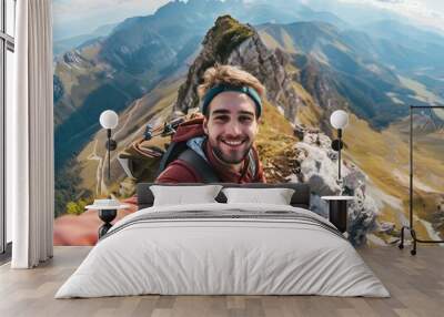 A young hiker man taking a vertical selfie portrait on the summit of a mountain, with a breathtaking view in the background. The happy guy is smiling at the camera Wall mural