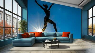 Silhouetted female winner figure jump against vibrant blue sky with sun. Freedom, inspirational, achievement, ambition concept. Girl athlete sculpture in sports arena, stadium. Sportswoman statuary. Wall mural