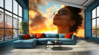 Young woman looking up at the sky at sunset Wall mural