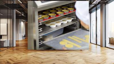 A uniformed cook puts pieces of cake in the refrigerator Wall mural