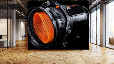 Detailed close-up of a modern camera lens with vibrant orange elements and sleek black design against a dark background Wall mural