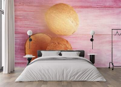 Two coconuts one whole the second is broken on a wooden background Wall mural