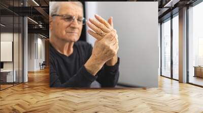 Elderly person massaging his hands Wall mural