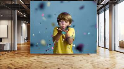 beautiful child blowing confetti on colored blue background. Wall mural