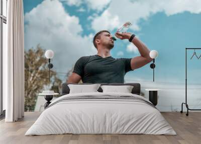 A man is drinking water from a bottle. Wall mural