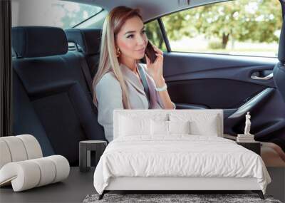 Beautiful woman car interior passenger, phoning, working road, tablet touch screen. Business VIP taxi rental car sharing city. Summer girl autumn city. Strict suit, long hair casual makeup. Wall mural